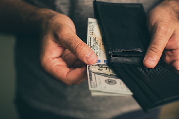 Man looks in the wallet cash wealthy man counting his money close up