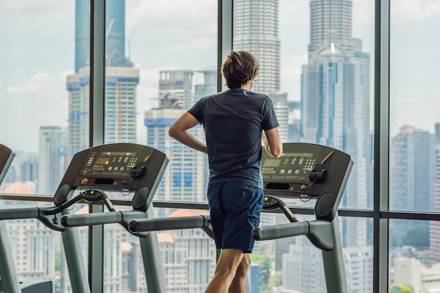 Man loopt in een sportschool op een loopband tegen de achtergrond van een grote stad. concept voor sporten, fitness en een gezonde levensstijl