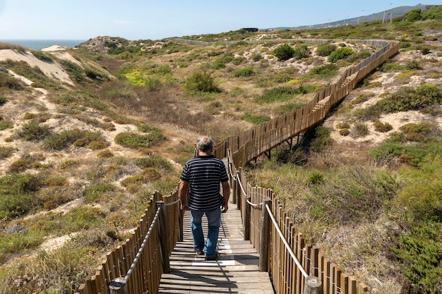 Man loopt op het houten pad van Guincho door de zandduinen