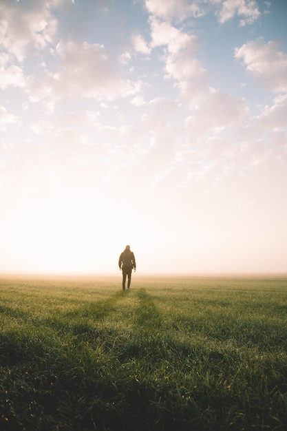 Man loopt op het veld tegen de hemel tijdens de zonsondergang
