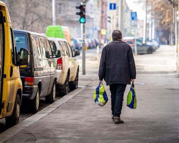 Man loopt over straat met aankopen in plastic zakken