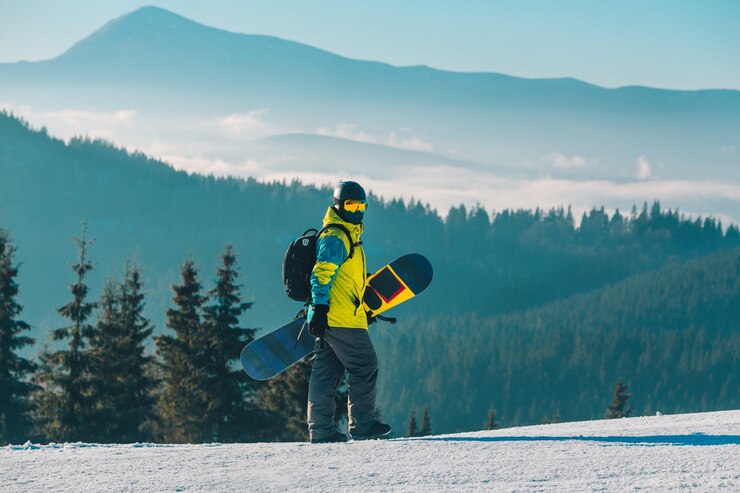 Foto man lopen door heuvel met snowboard bergen op background