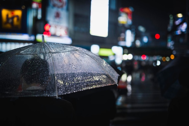Man lopen met een transparante paraplu in een stad 's nachts