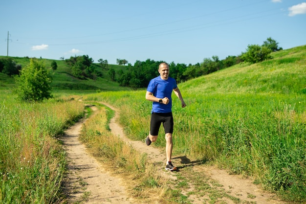 Man loper die op de landelijke weg loopt, draagt een zonnebril en een blauw t-shirt