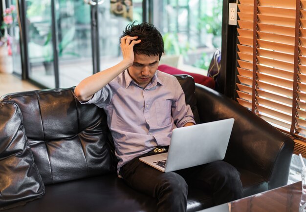 Man under a lot of stress using laptop computer in cafe