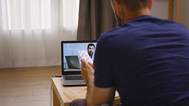 Man luistert naar zijn arts tijdens een videogesprek tijdens de quarantaine van het coronavirus.