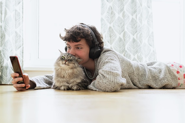 A man lying on the floor with a cat on his head