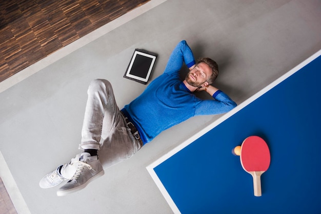 Man lying on the floor with tablet in break room of modern office