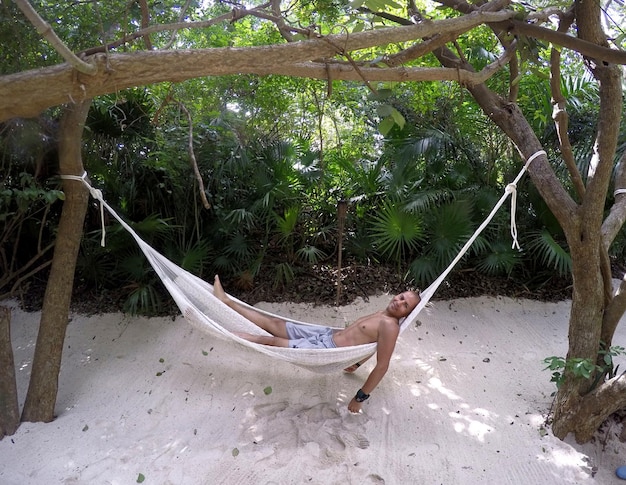 Foto uomo sdraiato su un'amaca contro gli alberi sulla spiaggia