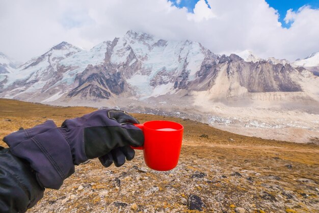 Man lying on a hill with a cup of fresh milk of yakmu female of
yak animal view of mountains and sky in gorakshep village nepal
everest base camp trail route nepal trekking