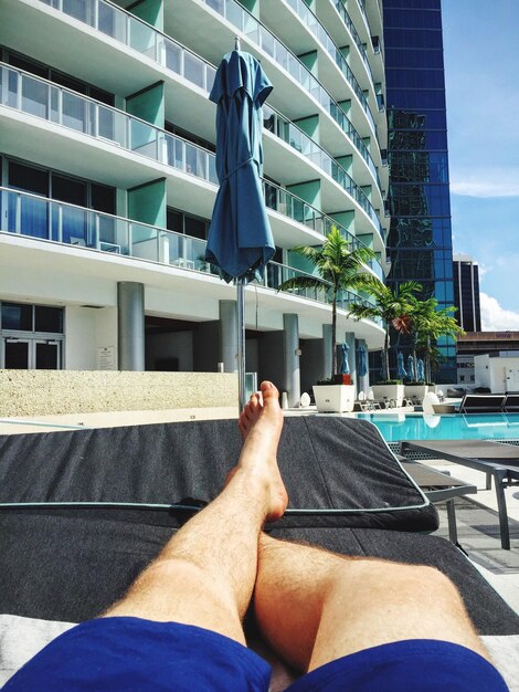 Foto uomo sdraiato accanto alla piscina dell'hotel