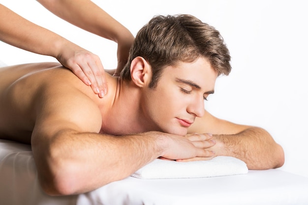 Man lying on a massage table is massaged by two female hands