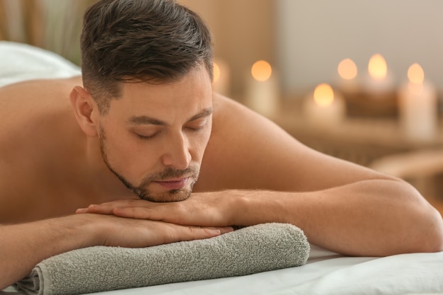Photo man lying on massage table in spa salon