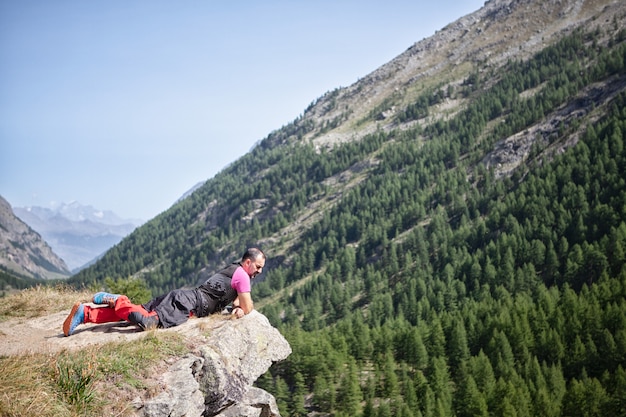 Man lying on precipice looking at mountainous landscape