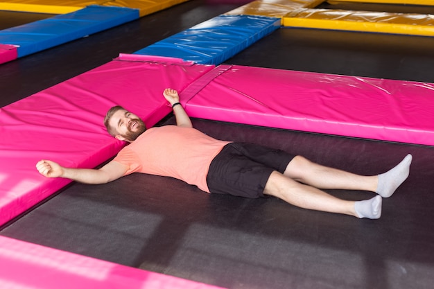 Man lying on a trampoline indoors, top view