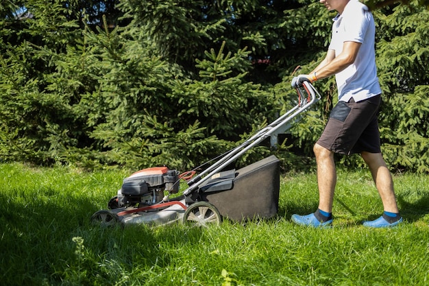 Man maait hoog gras in de tuin