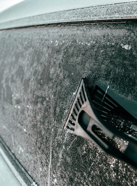 Man maakt een ijskoud raam van een auto schoon met een ijskrabber Koude sneeuw- en ijzige ochtend Focus op de ijskrabber