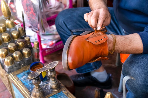 Man maakt schoenen schoon met schoensmeer op straat, oude methode