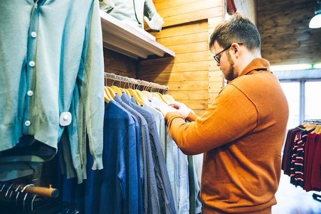 man make shopping in store choose shirts in shop