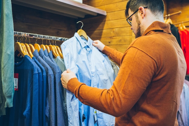 Man make shopping in store. choose shirts in shop