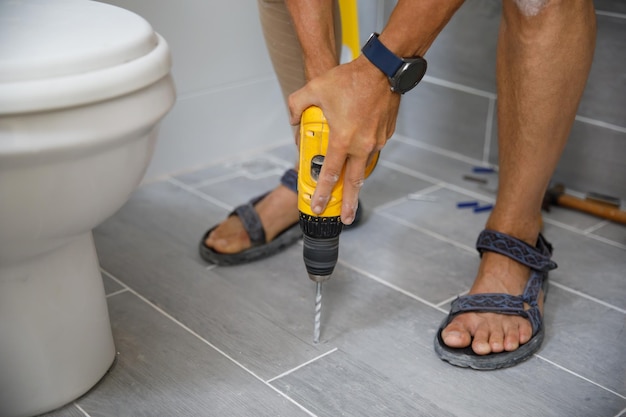 A man makes repairs in the bathroom using a puncher