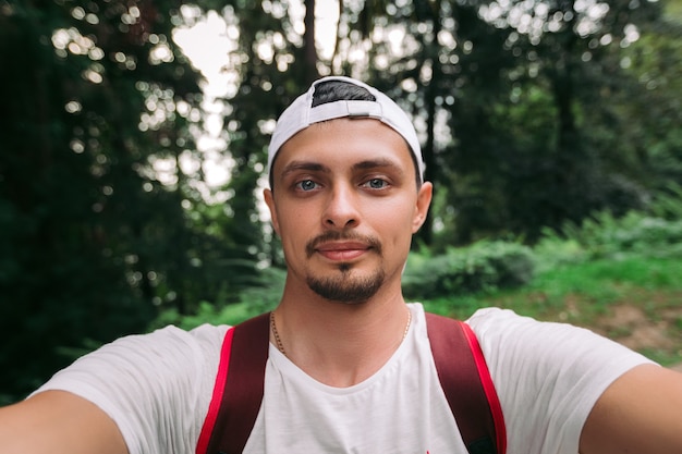 Man makes selfie in forest in summer day