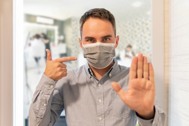 Foto l'uomo fa un gesto di arresto e indica la maschera. non entrare, modalità maschera