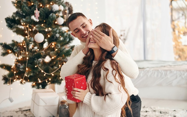 Man makes surprise for his girlfriend Young romantic couple celebrates New year together indoors