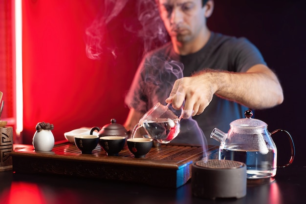 한 남자가 중국 전통 전통에 따라 기구로 차 탁자에서 차를 만들고 있다