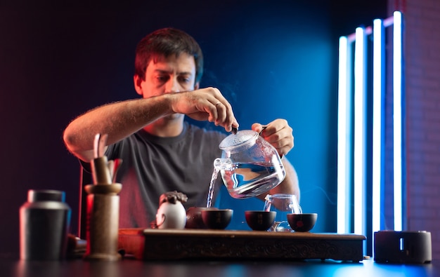 A man makes tea at a tea table with appliances according to the traditional Chinese tradition