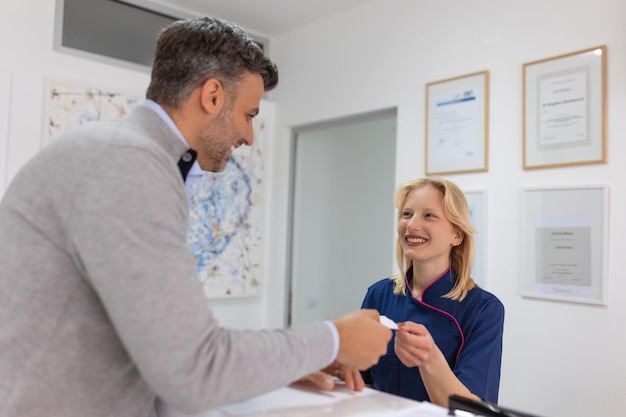 Man making an appointment with medical staffs at reception desk in hospital Medical staff and nurse receptionist talking to patient in front of the reception counter in hospital