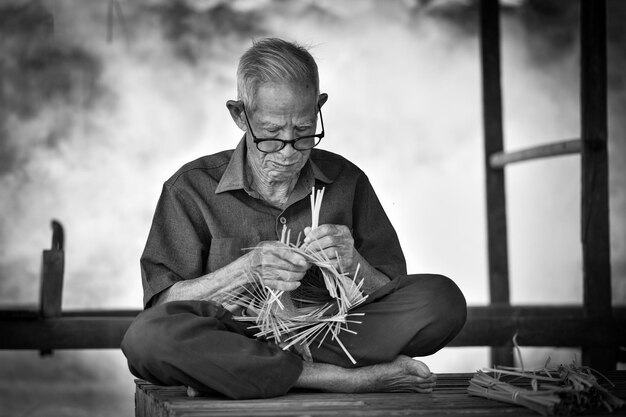 man making basket while sitting on bench