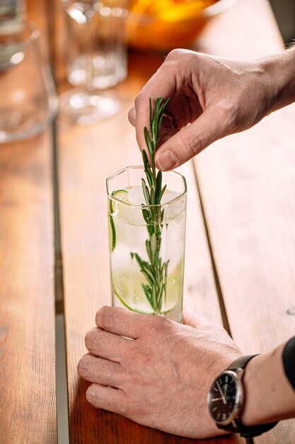 Man making fresh gin tonic cocktail with lime