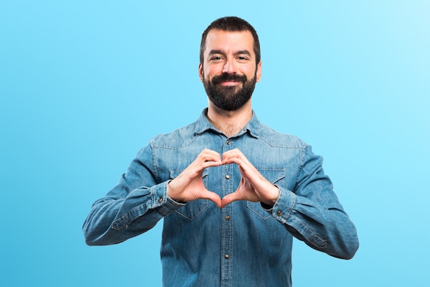 Foto l'uomo che fa un cuore con le mani su sfondo colorato