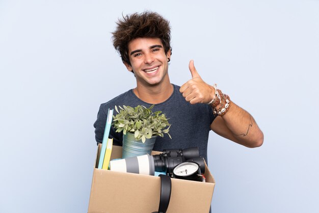 Man making a move while picking up a box full of things giving a thumbs up gesture