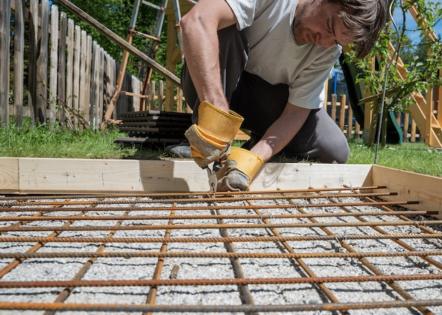 ワイヤーとペンチで棒鋼を切り取って網を作る男