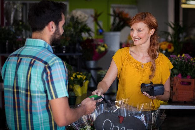 Man making payment with his credit card to female florist