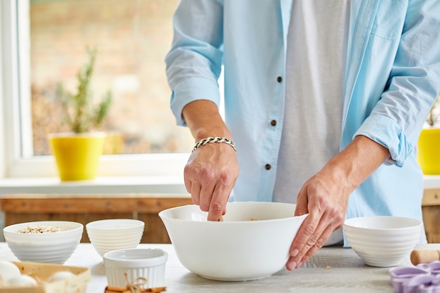 男性、男性がボウルで生地を作り、自宅でキッチンでこね、クッキーの準備、家庭料理。