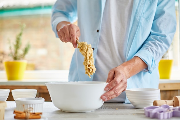 Man, male forming the dough in Bowl and kneading at home in the kitchen, preparation for cookies, home cooking.