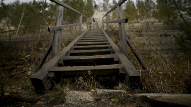 Man man going up stairs footage the old wooden steps on a hill rising on either side grass wood