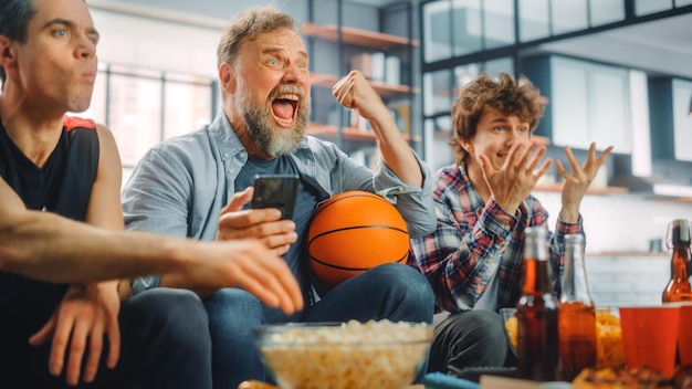 A man and a man watching a basketball game on a couch