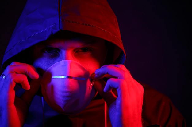 A man in a mask and chemical protection suit in red and blue light. Fight against the virus. COVID-19