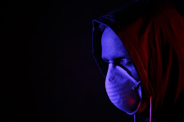 赤と青の光の中でマスクと化学防護服を着た男。ウイルスと戦ってください。 COVID-19（新型コロナウイルス感染症