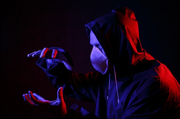 A man in a mask and chemical protection suit in red and blue light. Fight against the virus. COVID-19