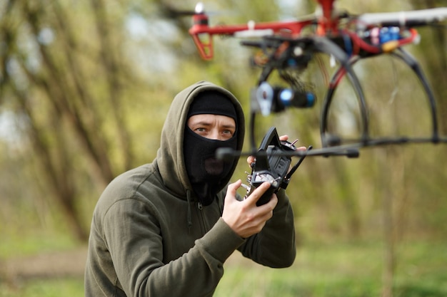 Man in mask operating a drone with remote control