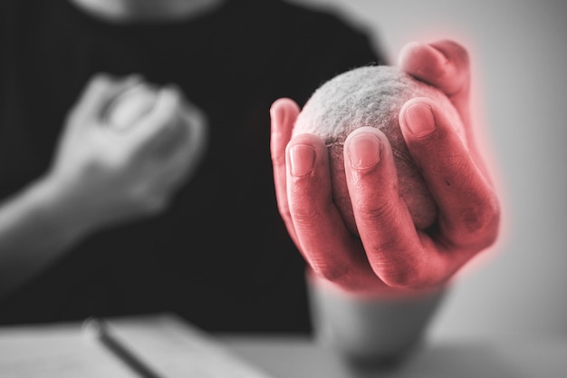 The man massages his finger by tennis balls Office syndrome concept Pain symptom area is shown with red color Extreme close up shot Black and white tone