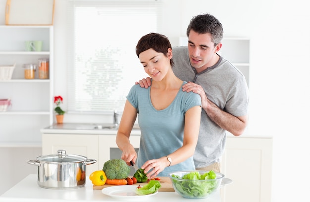 Uomo che massaggia la moglie mentre taglia le verdure