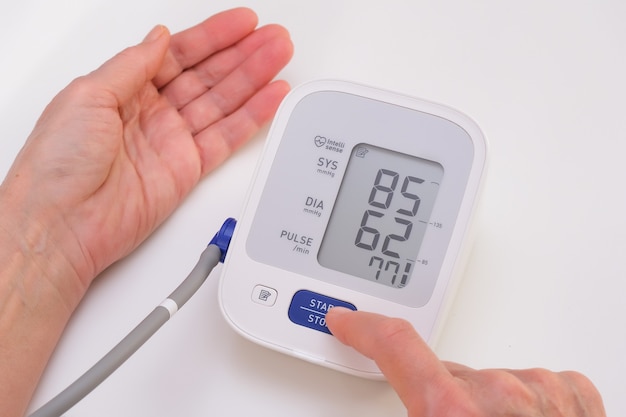 Photo man measures blood pressure, white background. arterial hypotension. hand and tonometer close up.