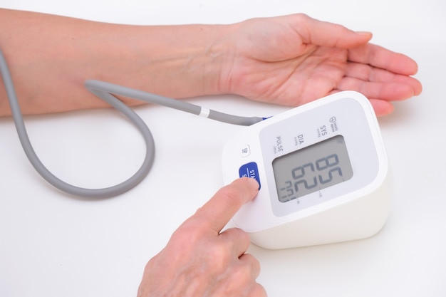 Man measures blood pressure, white background. arterial hypotension. hand and tonometer close up.