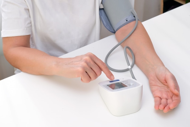 Man measures blood pressure, white background. arterial hypotension. hand and tonometer close up.